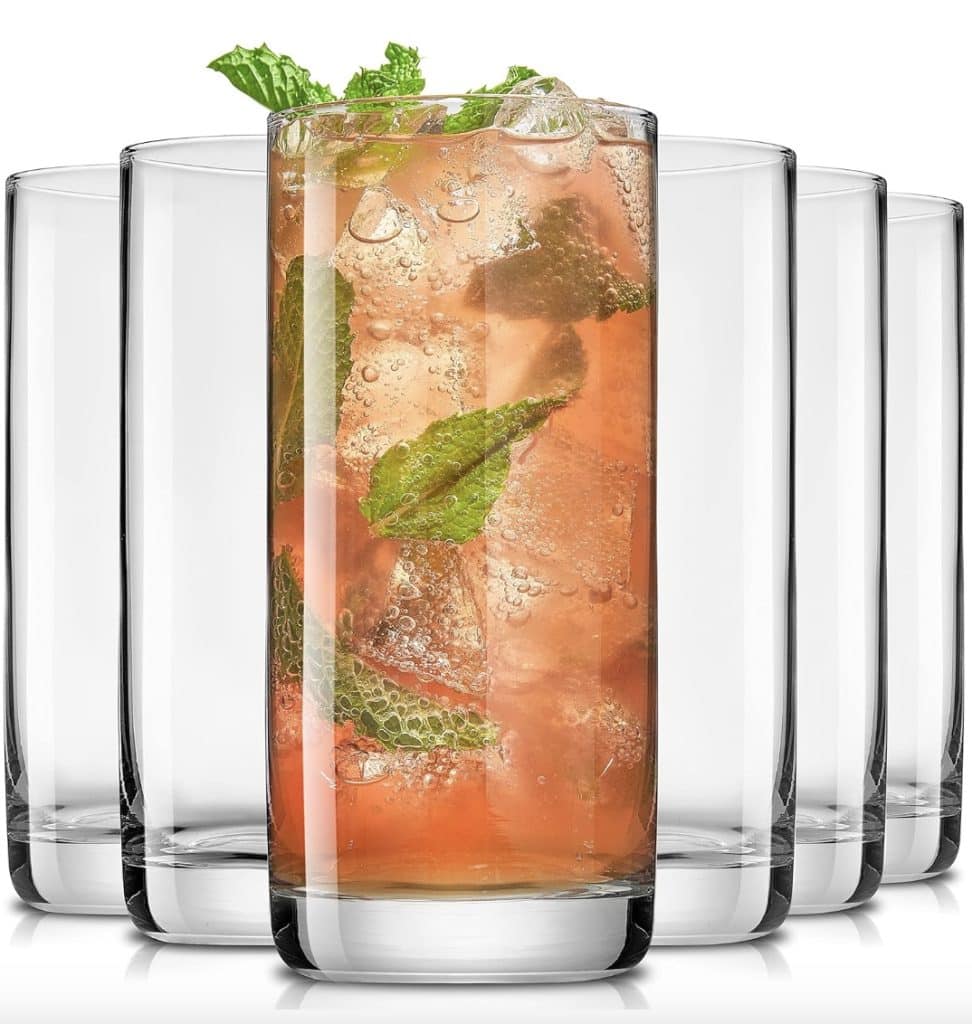 Tall, clear drinking glasses are arranged in a semicircle, with the front glass filled with a pinkish beverage reminiscent of easy summer mocktail recipes, complete with ice cubes and mint leaves.